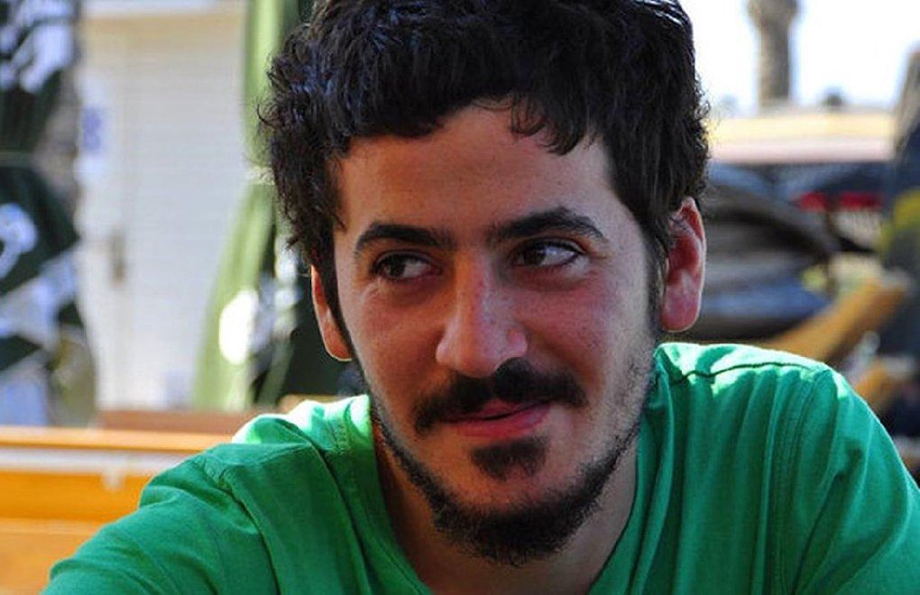 Portret van Ali Ismail Korkmaz. Hij glimlacht. Hij draagt een groen T-shirt.