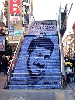 Een betonnen trap met op de stootborden een portret van Ali Ismail Korkmaz.