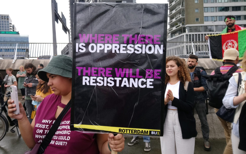 Een demonstrant met een BIJ1-protestbord met de tekst 'Where there is oppression, there will be resistance'.