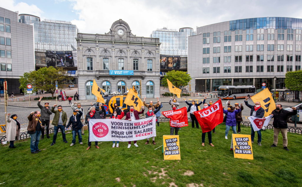 Groepsfoto van demonstranten vanuit een hoog standpunt. Je ziet allemaal mensen in het gras op een rotonde staan, met veel spandoeken en voor14-vlaggen.