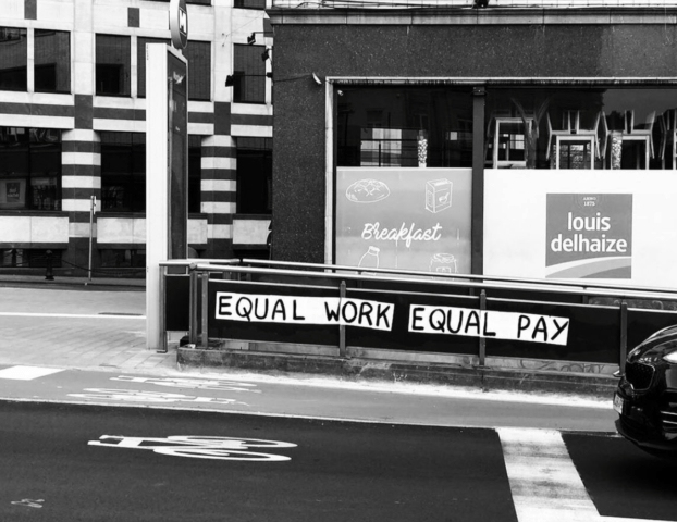 Een supermarkt langs de kant van de weg met ervoor een metro-ingang met daarop de tekst "Equal work equal pay".