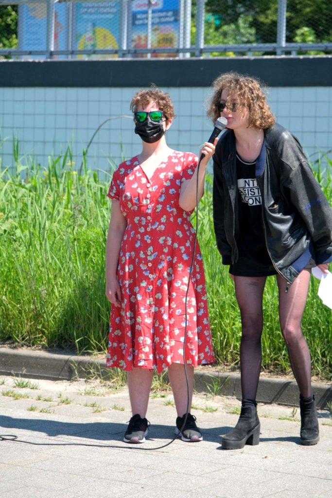 Een demonstrant voert het woord via een microfoon die wordt vastgehouden door de persoon naast hen.