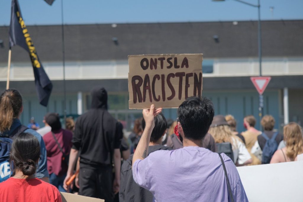 Demonstrant met een bord "Ontsla racisten".