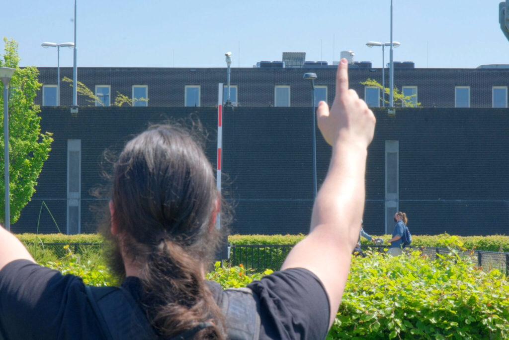 Een demonstrant heft de handen op richting het detentiecentrum.