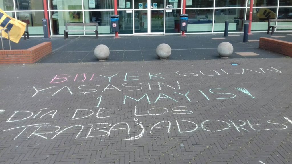 1 mei-teksten in verschillende talen, gekrijt op de stoep voor het ziekenhuis