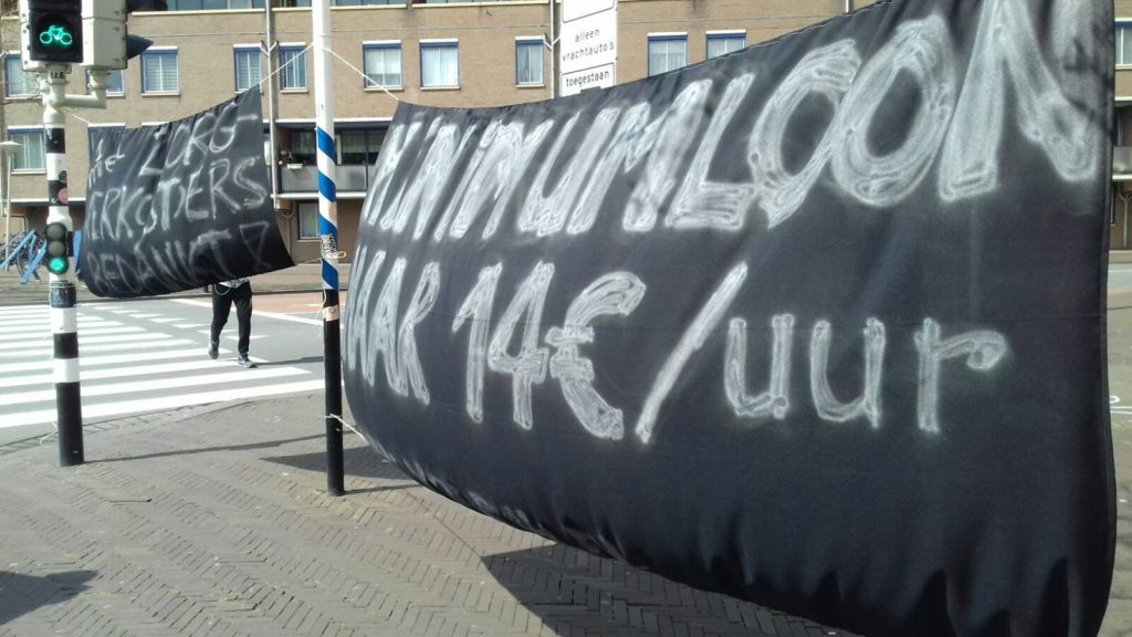 Grote zwarte spandoeken die zorgwerkers bedanken en oproepen tot een hoger minimumloon.