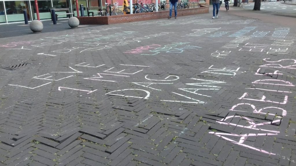 Overzicht van een heleboel krijtteksten, niet leesbaar door de hoek vanuit welke de foto is genomen.