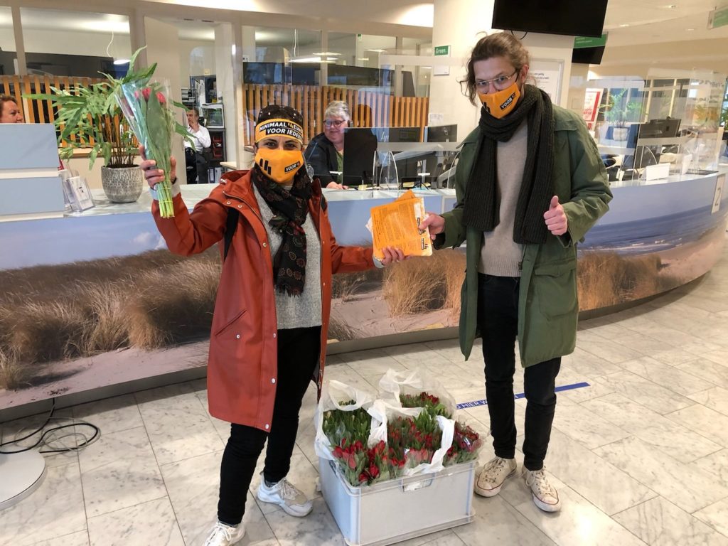 Voor14-activisten bij de balie van het ziekenhuis met bloemen en flyers.