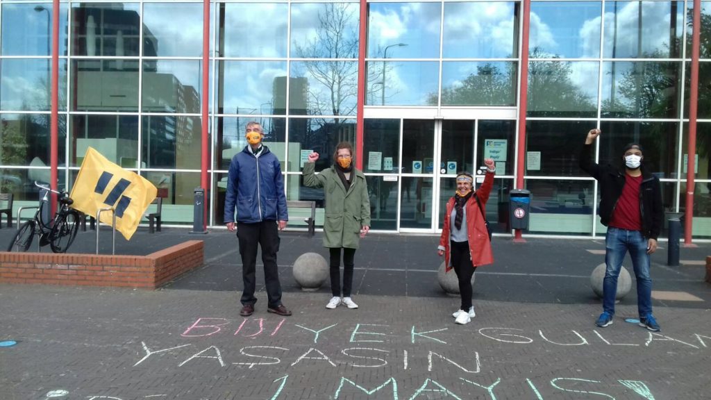 Vier demonstranten waarvan drie met geheven vuisten, voor de ingang van het ziekenhuis.