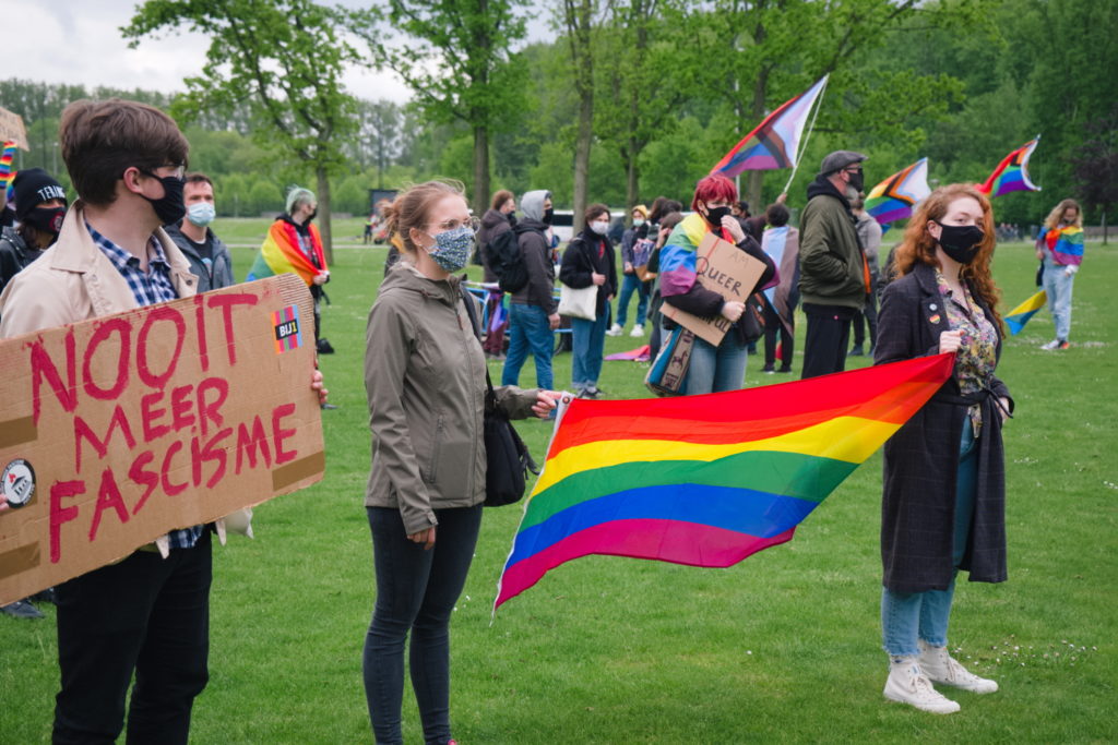 Twee deelnemers houden samen een regenboogvlag vast.