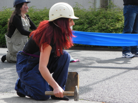 Optreden van vrouwengroep Street Amazons over hoe van alle kanten aan vrouwen getrokken wordt. Hier: werken in de fabriek.