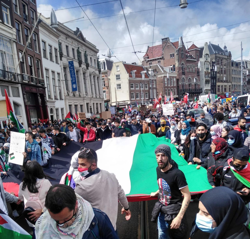 Demonstranten dragen een enorme Palestijnse vlag mee in Amsterdam.