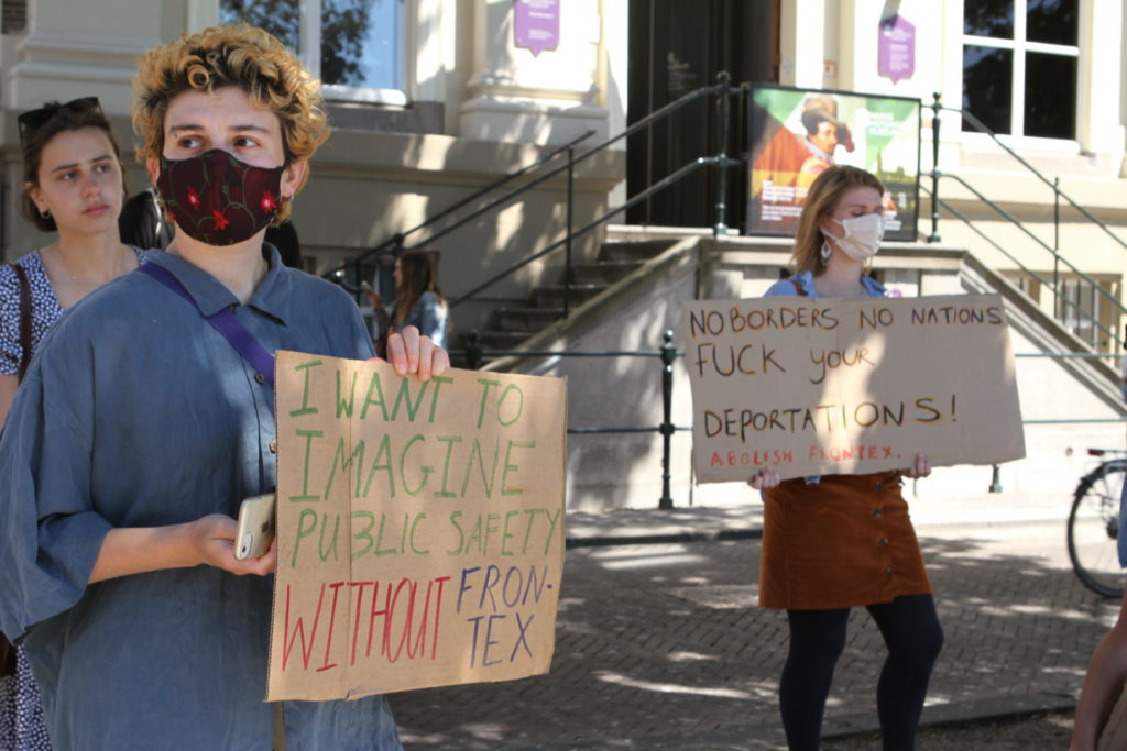 Twee demonstranten met hun borden. Ze staan voor het Mauritshuis.