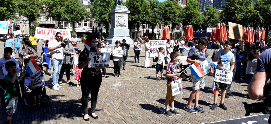 De demonstranten rondom een beeld op het plein. Op de achtergrond terrassen.