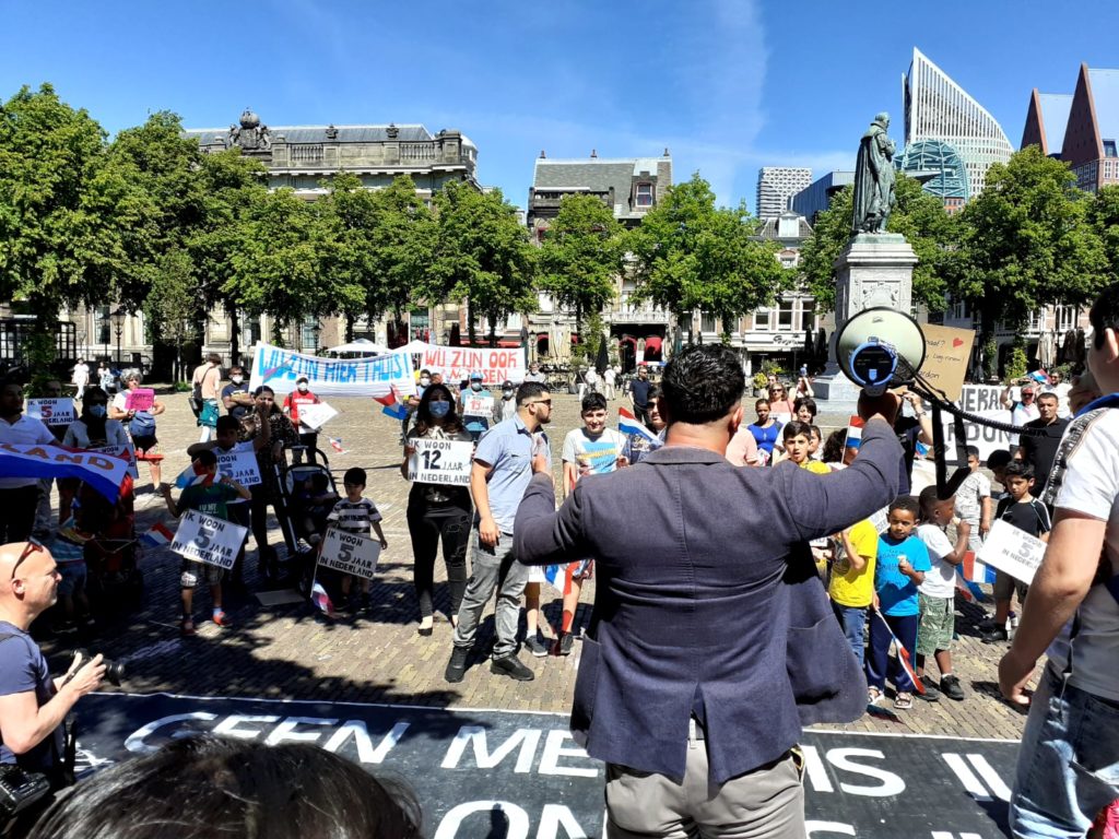 We kijken op de rug van één van de sprekers richting de demonstranten.