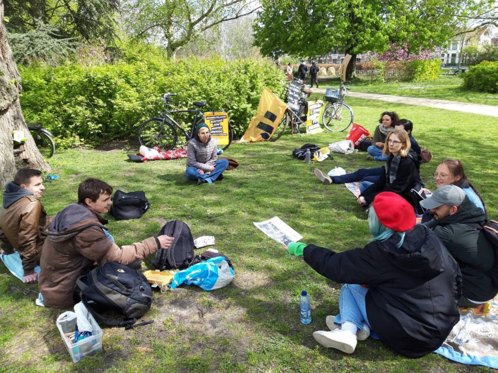 De demonstranten zitten in de zon in het gras.