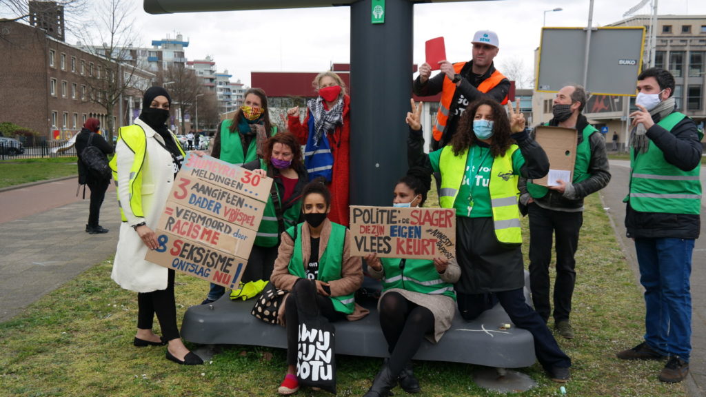 Een groep demonstranten poseert voor de foto. Twee borden zijn leesbaar, de ene met de tekst "Humeyra 30 meldingen, 3 aangiften, dader vrij spel = vermoord door racisme en seksisme, ontslag nu!" en de andere met de tekst "Politie: de slager die zijn eigen vlees keurt".