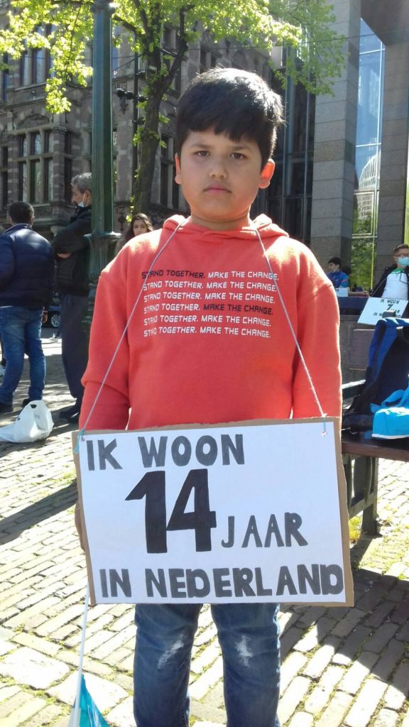 Kind met een bord "Ik woon 14 jaar in Nederland".