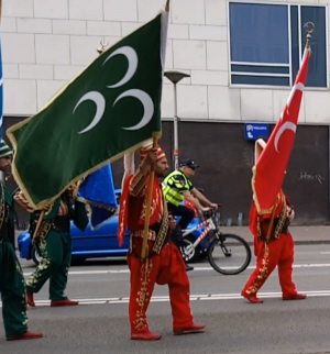 Grijze Wolven-symbolen voorop tijdens de optocht: een groene en een rode vlag met drie halve manen.