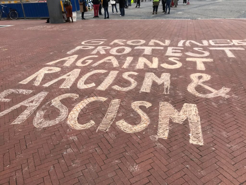 Grote stoepkrijttekst "Groningen protest against racism & fascism".