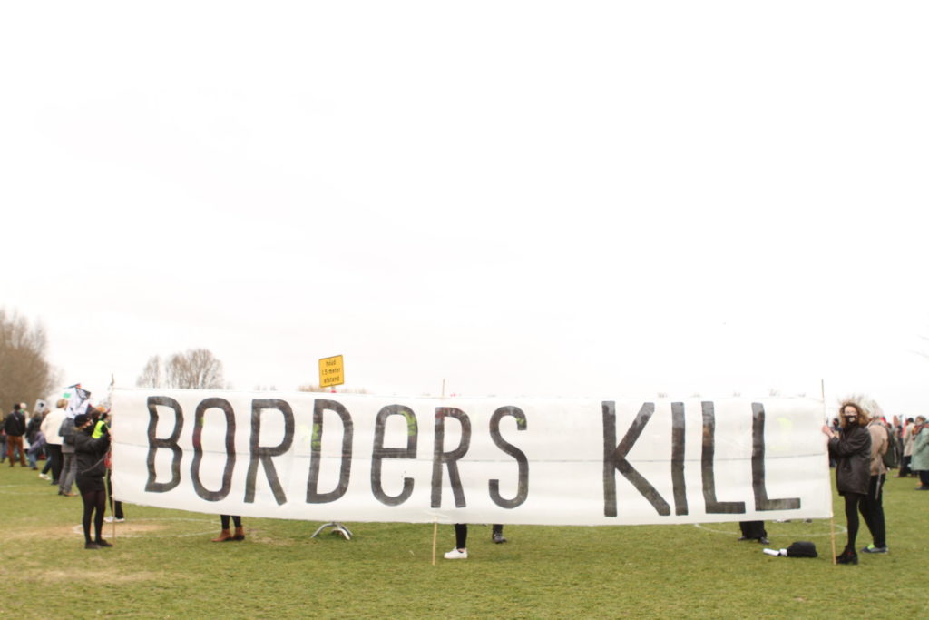 Een enorm spandoek van misschien wel zes of zeven meter breed, vastgehouden door twee personen, met in hele grote letters de tekst "Borders kill".