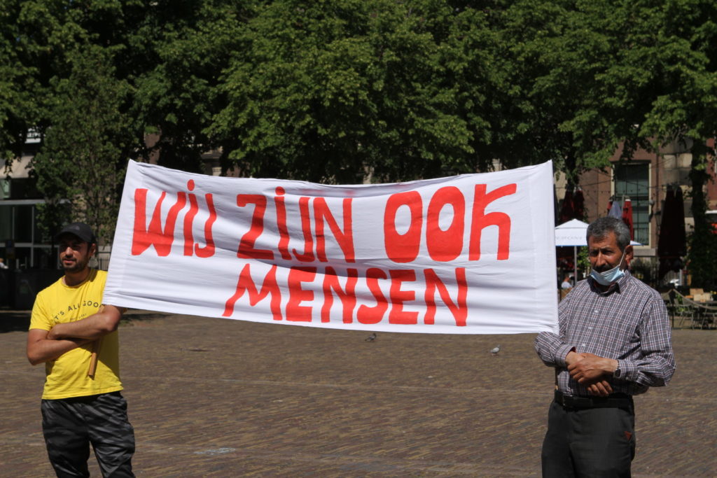 Twee demonstranten met een spandoek met de tekst "WIJ ZIJN OOK MENSEN".