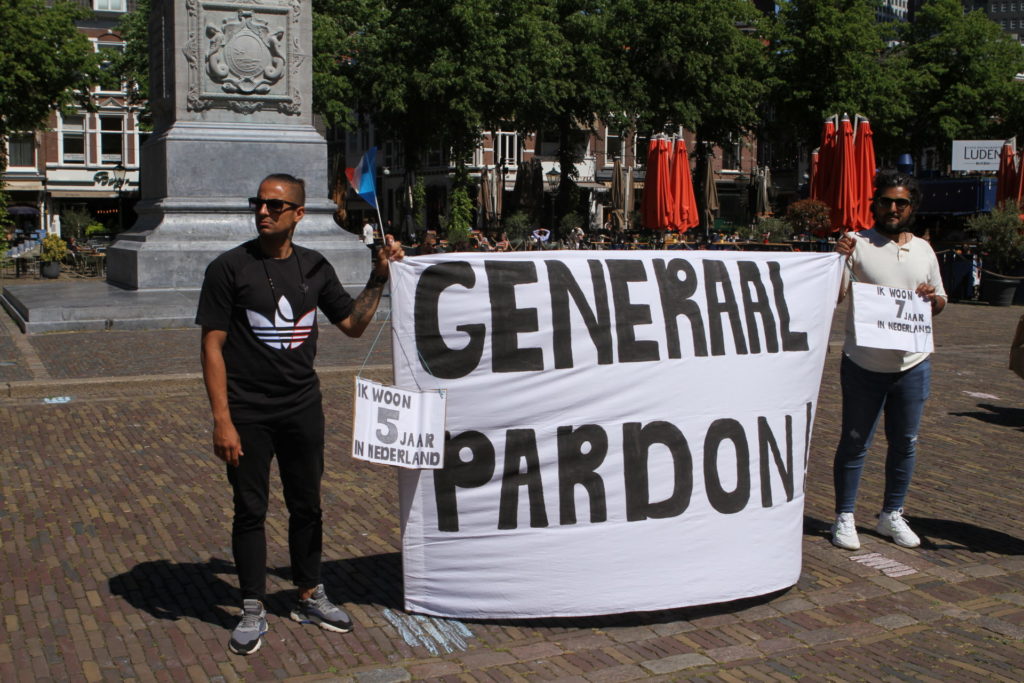 Twee demonstranten met een groot spandoek met de tekst 'GENERAAL PARDON'.