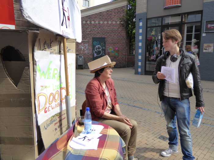 Actievoerster in gesprek met geïnteresseerde voorbijganger.