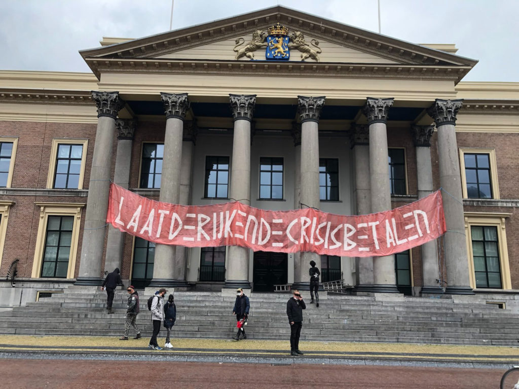 Gerechtshof in Leeuwarden met op de pilaren van de entree een enorm spandoek met de tekst "Laat de rijken de crisis betalen".