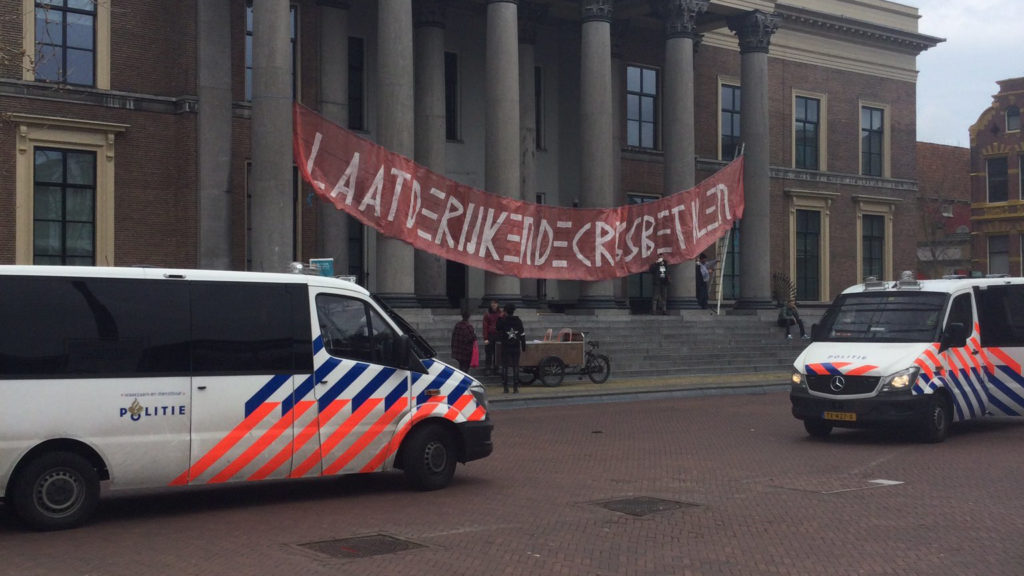 Twee politiebussen bij het Gerechtshof in Leeuwarden, ze zijn er vanwege het spandoek.