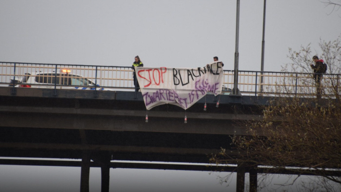 Het spandoek in Nijmegen, terwijl het verwijderd wordt door de politie.