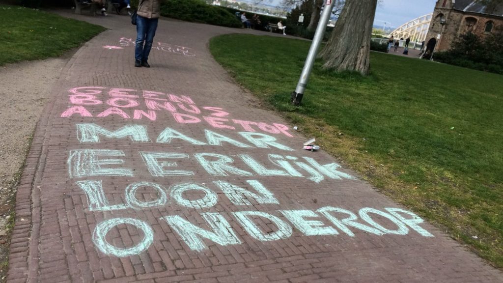 Krijttekst "Geen bonus aan de top, maar eerlijk loon onderop".