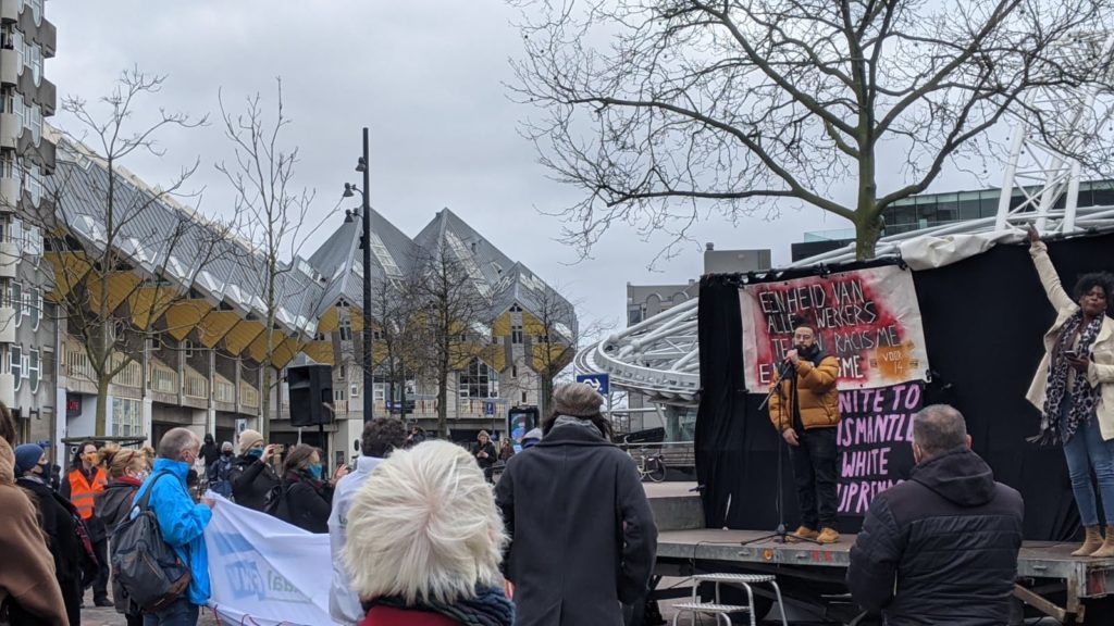 Spoken word-artiest Patrick Ribeiro aan het woord. Op de achtergrond de kubuswoningen.