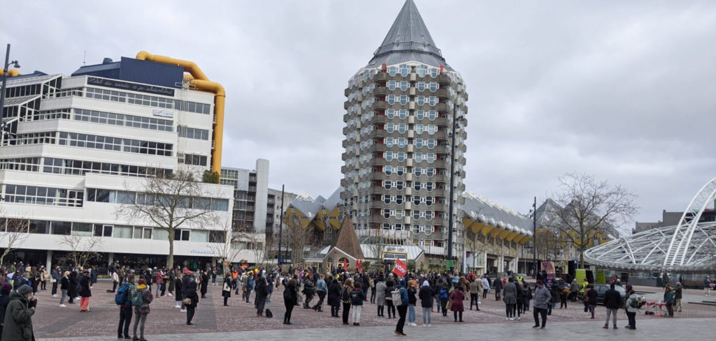 De openbare bibliotheek en het potloodgebouw met op het plein daarvoor tientallen demonstranten.