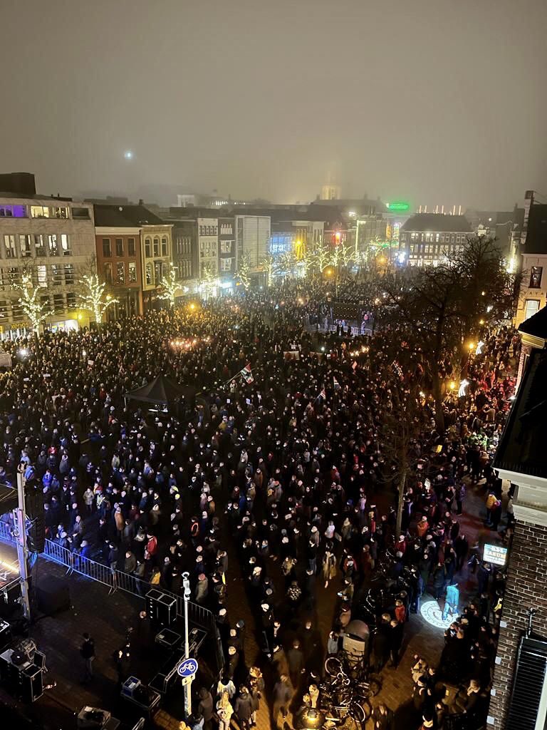 Een luchtfoto van een grote groep mensen met fakkels 's avonds.