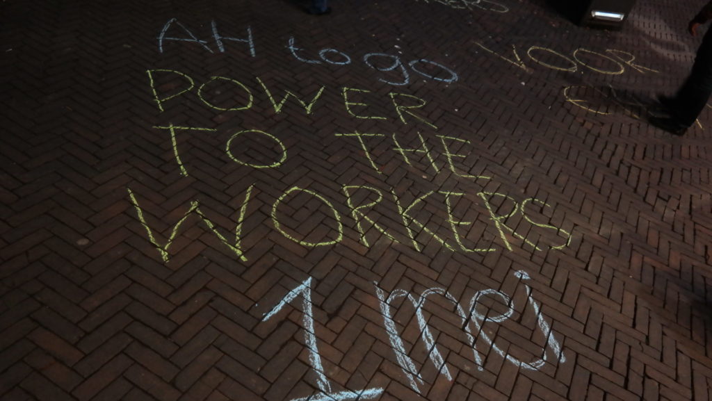 Krijttekst op straat: "AH To Go power to the workers 1 mei"