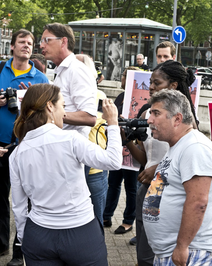 Eerdmans discussieert buiten met tegendemonstranten, terwijl Umar iedereen filmt die iets tegen haar zegt.