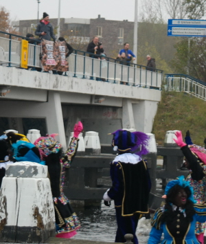 De bekende "Zwarte Piet is racisme"-spandoeken linksboven terwijl Sinterklaas de stad binnenvaart