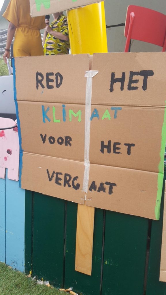 Een bord met de tekst "Red het klimaat voor het vergaat".