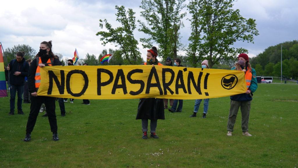 Drie activisten met het "No pasarán!"-spandoek.