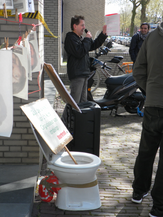 De speech. De andere deelnemers aan het protest brengen we niet in beeld omdat hun klantmanagers niet persé hoeven te weten dat ze actie voeren. Op de voorgrond de pleepot die we altijd meenemen naar onze acties: "schijt aan dwangarbeid!"